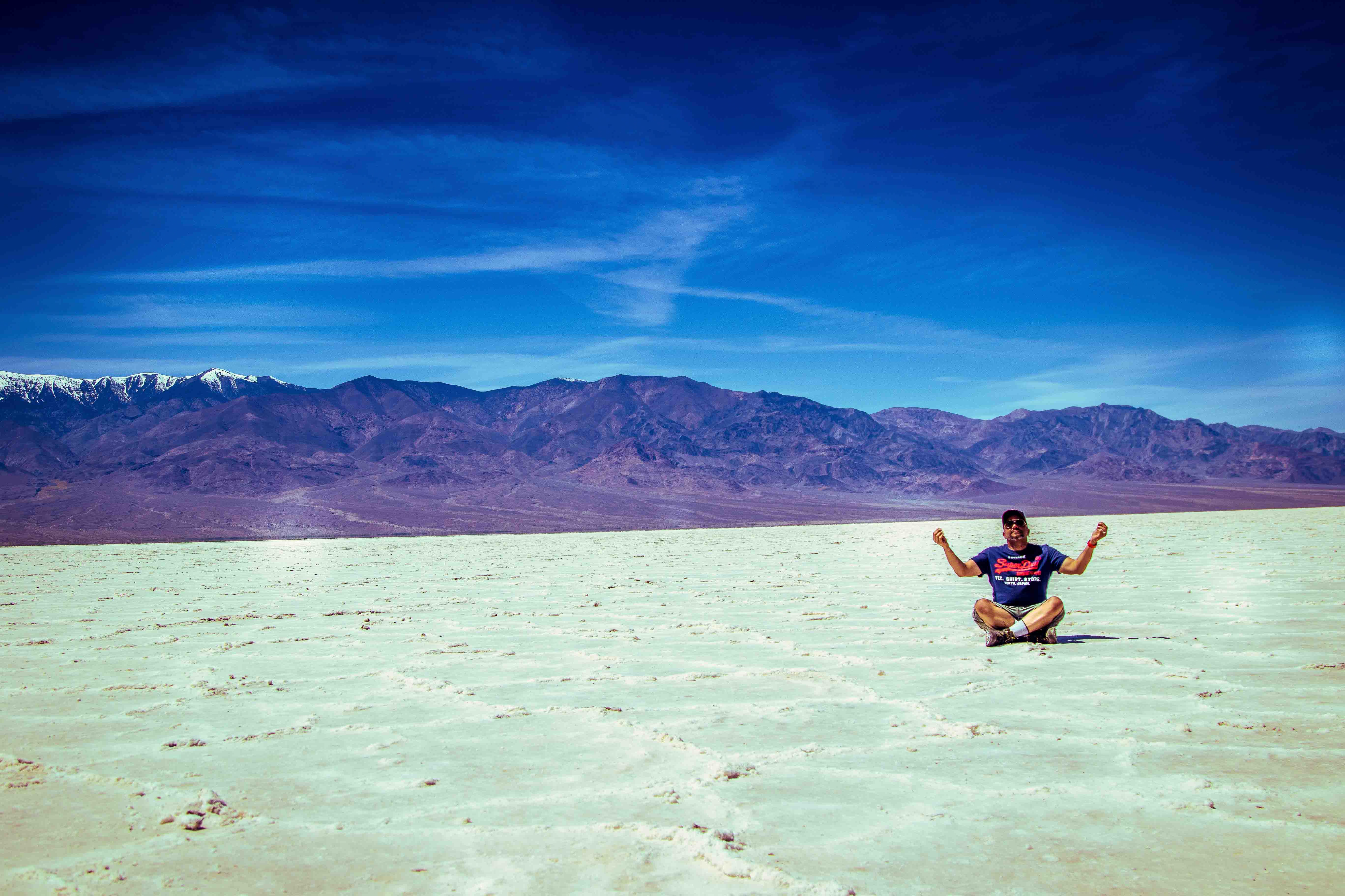 Badwater Basin — a lone visitor meditates on the blinding white salt flat, Panamint Range behind